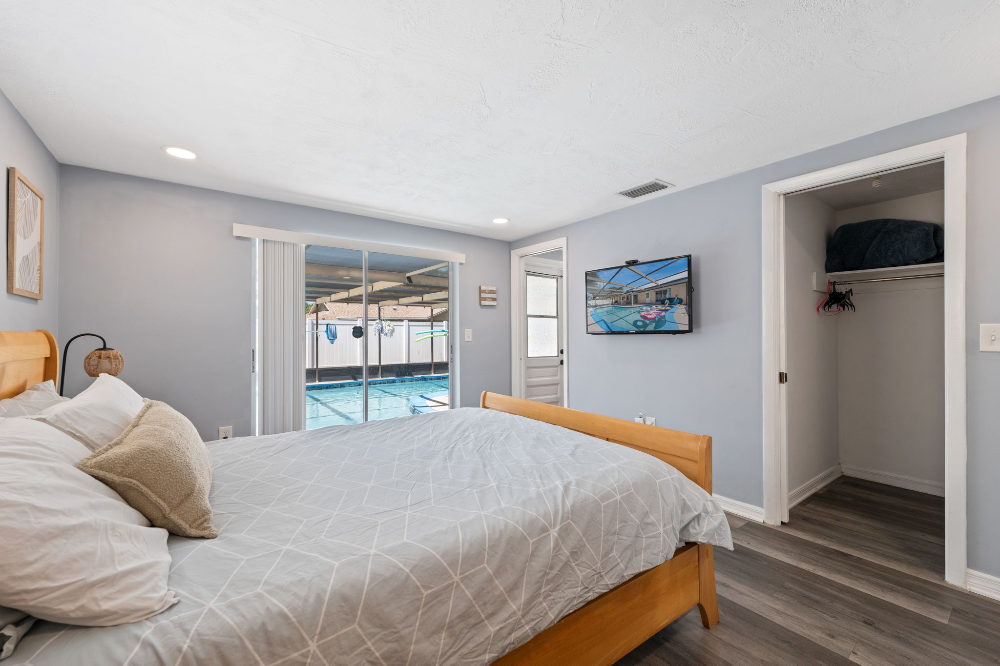 Une chambre à coucher avec un lit, une armoire, un tableau et une vue sur une piscine.
