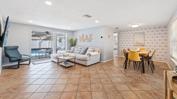 Un grand espace de vie comprenant un canapé, une table à manger avec des chaises et un balcon avec vue.