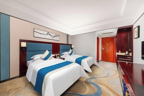 A hotel room with two beds, a desk, a TV, and a painting on the wall. - Jiahua Business Hotel (Shaoguan)