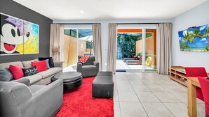 A modern living room with a grey sofa, red cushions, a red rug, and a large cartoon print on the wall. - The Mouse’s House/Private Retreat/Close to Disney (Kissimmee)