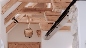 Un plafond en bois avec des poutres apparentes et un mur rustique, laissé à l’état brut.