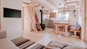 Un intérieur rustique en bois, comprenant un coin repas, une cheminée et une grande fenêtre.