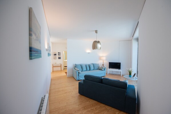 Un salon moderne avec un canapé, un téléviseur et une lampe.