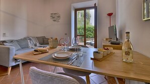 A dining area with a table set for two, a bottle of liquor, and a view of the outdoors.