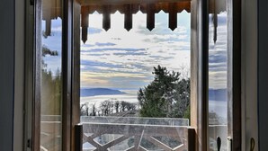 Eine Holztür führt zu einem Balkon mit Blick auf eine verschneite Landschaft und einen klaren Himmel.