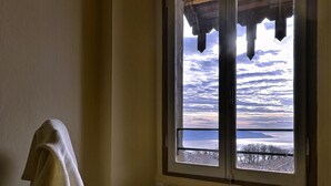 Ein Zimmer mit Meerblick durch ein Fenster, ein Heizkörper und ein Stuhl mit einem Handtuch.