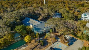 An aerial view of a property with a large house, a swimming pool, and a water tower. - Ocean Dunes 2306B | Across from Beach + Community Pool! (Kure Beach)