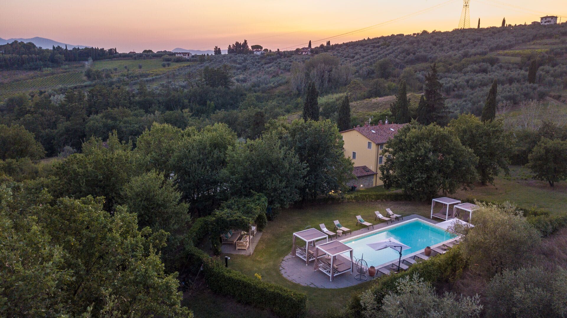 A villa with a swimming pool surrounded by lush greenery and hills.