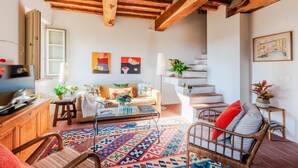 Un salon chaleureux avec un plafond en bois, un canapé, une table basse et un tapis à motifs.