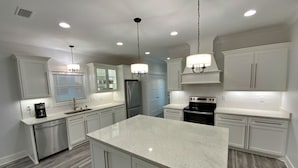A modern kitchen with white cabinetry, a large island, stainless steel appliances, and pendant lighting. - Updated - Pools, tennis, beach! (Gulf Shores)