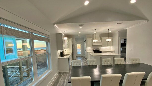 A modern kitchen with white cabinets, a central island, and pendant lighting. - Updated - Pools, tennis, beach! (Gulf Shores)