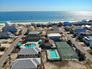 A coastal residential area with houses, a tennis court, and a swimming pool.
