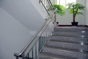 A staircase with a metal handrail and a potted plant at the top. - Lijiang Hotel (Xinyi Railway Station) (Xinyi)