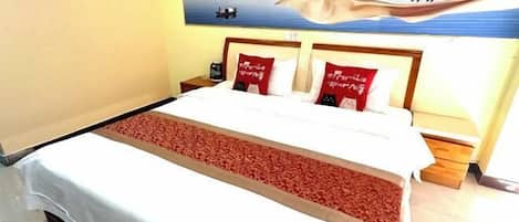 A hotel room with a large bed, two bedside tables, and a painting of deer on the wall.