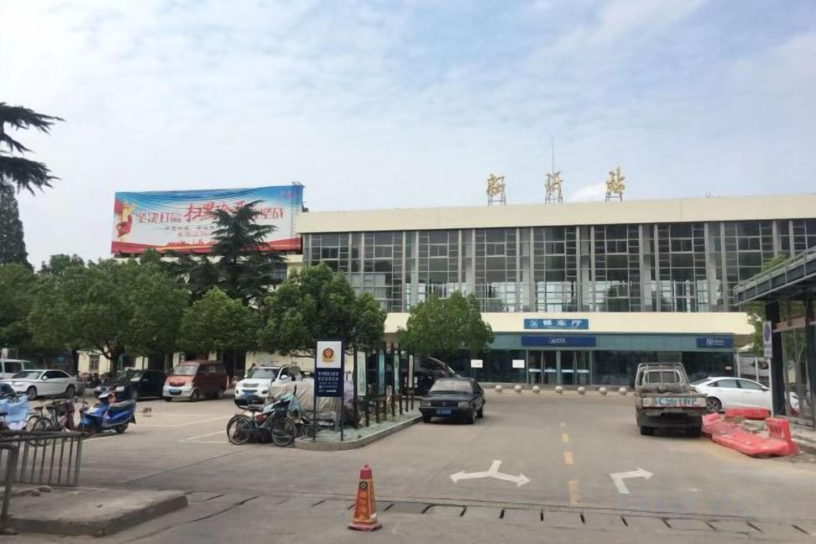 A building with a large sign, a parking lot, and a few vehicles.