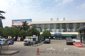 A building with a large sign, a parking lot, and a few vehicles. - Lijiang Hotel (Xinyi Railway Station) (Xinyi)