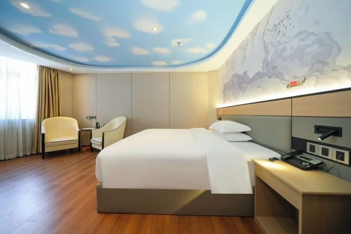 Hotelkamer met een bed, bureau, stoel en een groot muurschildering.