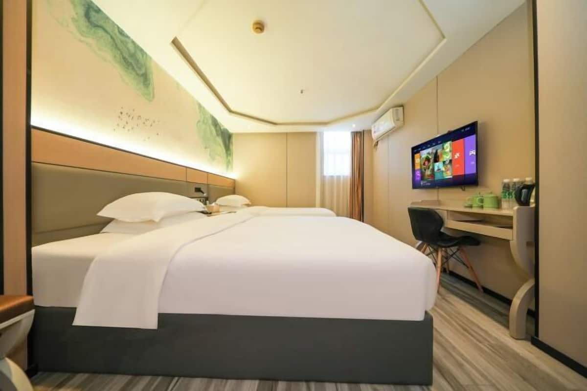 Hotelkamer met een groot bed, een bureau, een stoel, een televisie en een wanddecoratie.