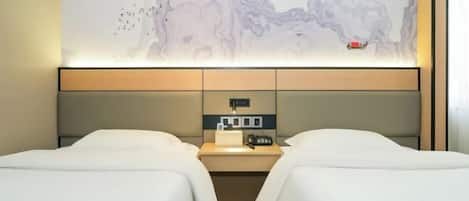 A hotel room with two beds, a nightstand, a wall-mounted control panel, and a large abstract artwork.