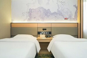 Habitación de hotel con dos camas, una mesita de noche, un panel de control en la pared y una obra de arte abstracta de gran tamaño.