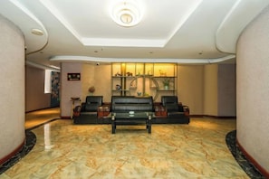 Una hall con reception, area salotto e una parete decorativa.