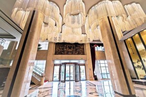 Een statig atrium met grote zuilen, een centrale trap en een decoratief plafond.