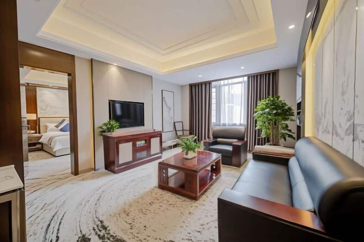 A modern living room with a sofa, a TV, a coffee table, and a potted plant.