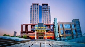 A modern hotel with a prominent entrance, multiple floors, and a clear sky. - Zhengda International Hotel (Jiangling)