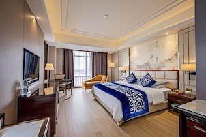Habitación de hotel con una cama grande, un escritorio, una silla y un televisor.