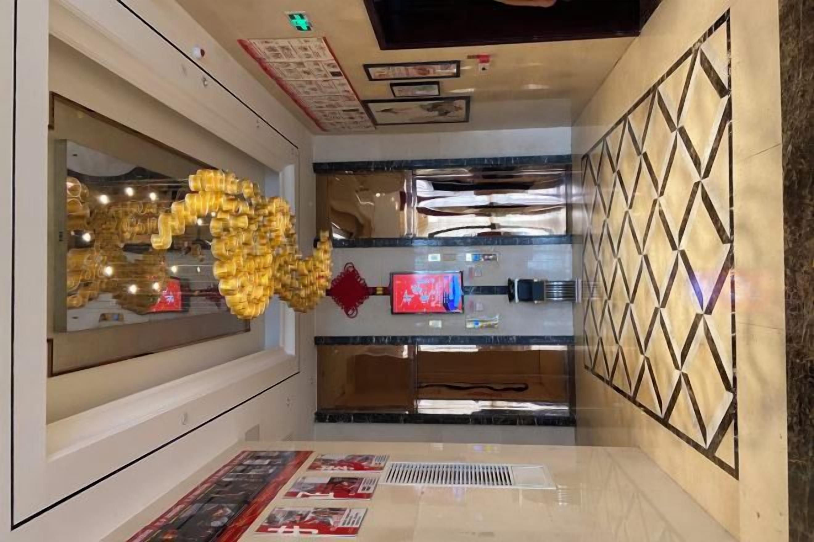 A hotel lobby with a modern design, featuring a large decorative golden sculpture, a reception desk, and a patterned wall.