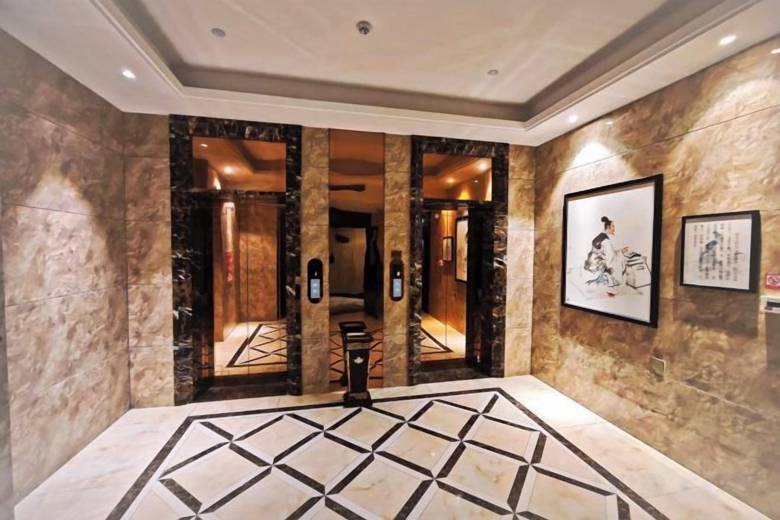 A lobby with marble walls, a geometric floor pattern, and framed artwork.