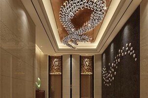 Un interior moderno con un diseño de techo singular, una escultura abstracta verde y paneles de pared con motivos.