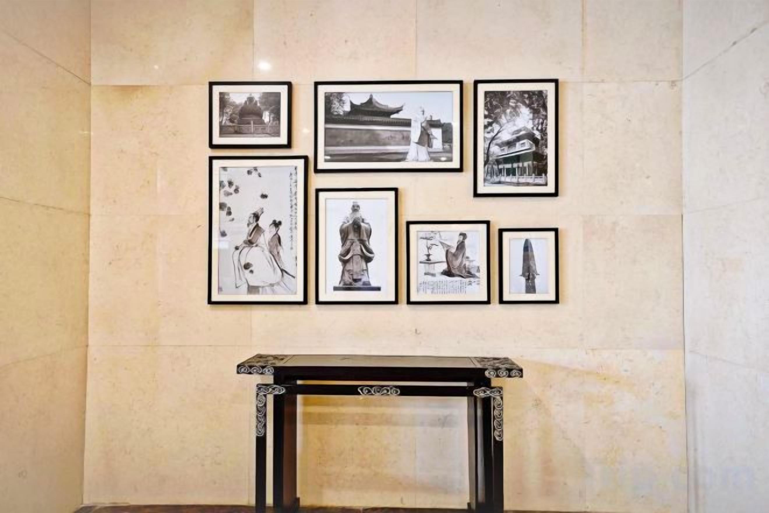 A wall with framed black and white photographs and a fireplace below.