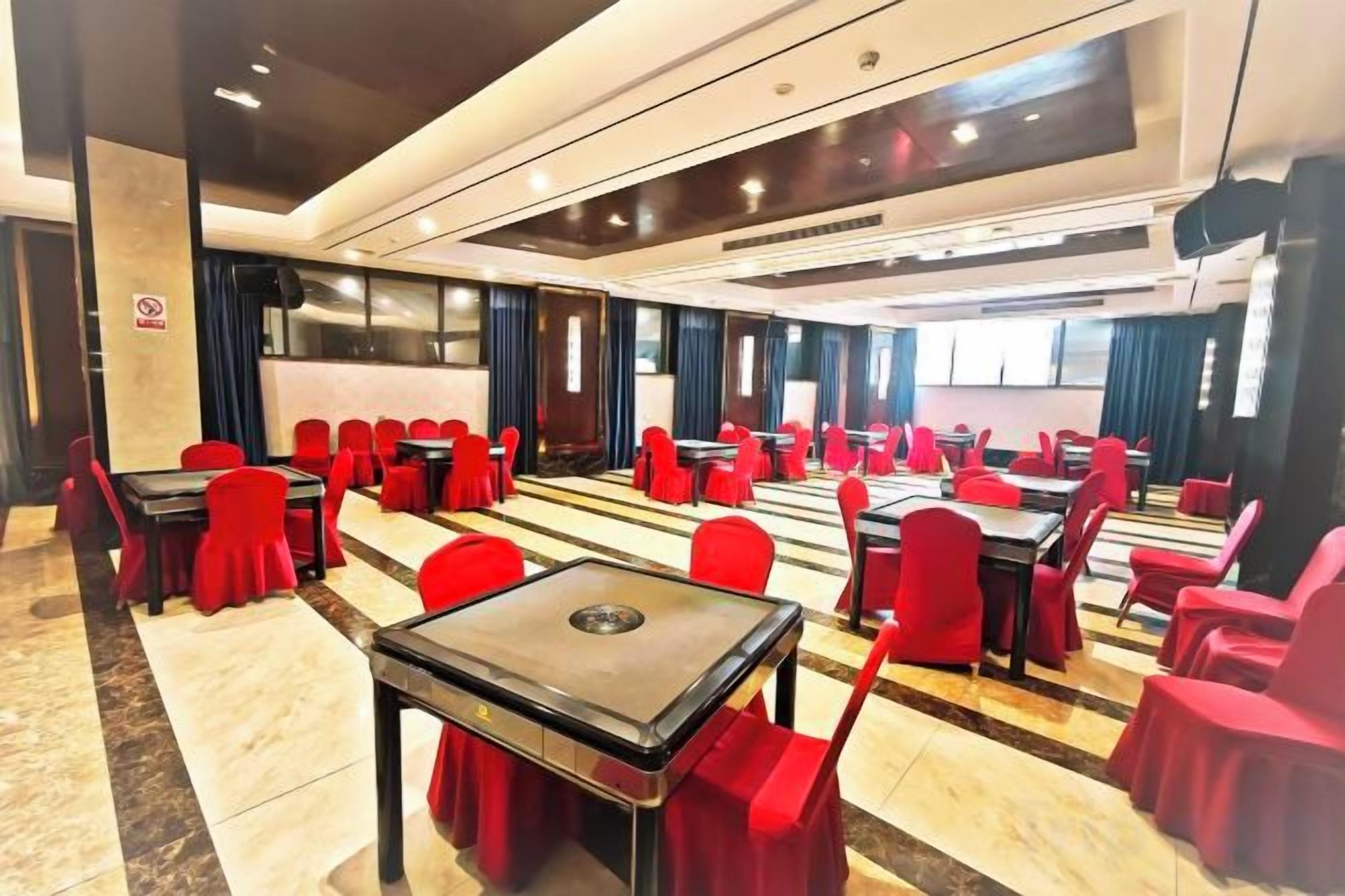 A conference room with multiple tables and chairs, arranged in rows.