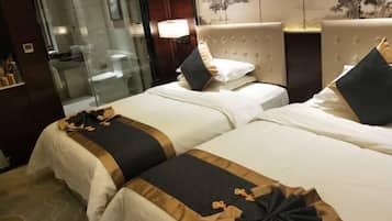 Ein Hotelzimmer mit zwei Betten, einer Duschkabine aus Glas und einer Wandlampe.