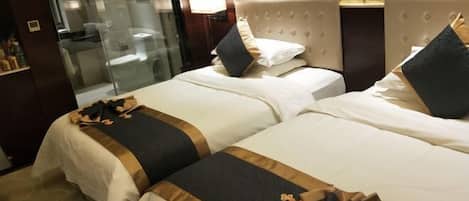 Ein Hotelzimmer mit zwei Betten, einer Duschkabine aus Glas und einer Wandlampe.