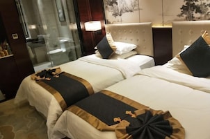 Habitación de hotel con dos camas, cabina de ducha de vidrio y una lámpara de pared.