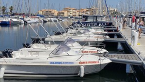Un puerto deportivo con barcos amarrados, un muelle de madera y edificios al fondo.