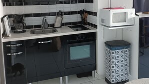 Una cocina moderna con gabinetes negros, encimera blanca, un microondas y un cubo de basura.