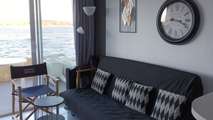 Una sala de estar moderna con un sofá gris oscuro, un reloj de pared redondo y una obra de arte enmarcada.
