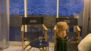A room with two chairs labeled "FERNAND" and "MARILOU" facing a large window overlooking a body of water.