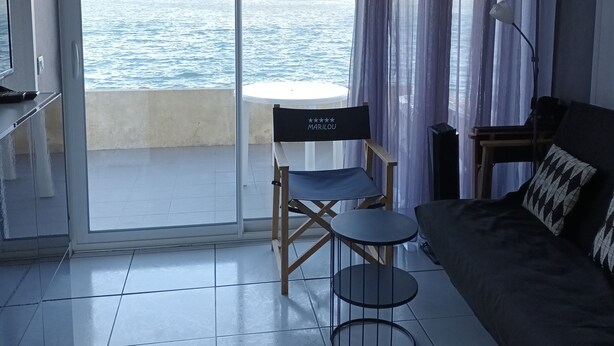 Una habitación con balcón, un sofá, una mesita y una silla.