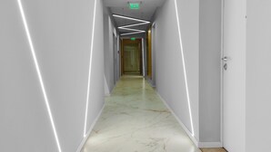 A corridor with white walls, marble flooring, and recessed lighting. - Studio Win Herastrau (Bucharest)