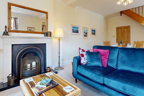 A living room with a fireplace, a sofa, a coffee table, and framed pictures on the wall.