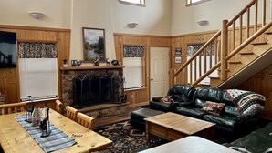 Una sala de estar acogedora con chimenea, muebles de madera y una escalera.