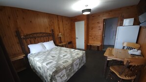 Una habitación con paneles de madera, una cama, una mesa y una silla.