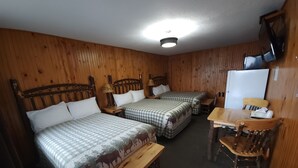 Una habitación tipo cabaña con dos camas, una mesa de madera, una silla y un televisor.