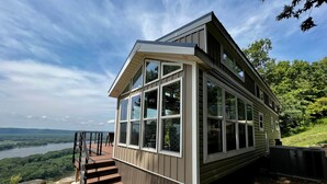 A modern house with large windows, a deck, and a view of a river and hills. - Paradise Point- Sleeps 2 HOT TUB (De Soto)