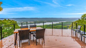 A wooden deck with a table and chairs overlooking a river and forested landscape. - Paradise Point- Sleeps 2 HOT TUB (De Soto)