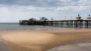 A pier extending into the water with buildings at the end. - Mode Winter Garden Apartments (Blackpool)